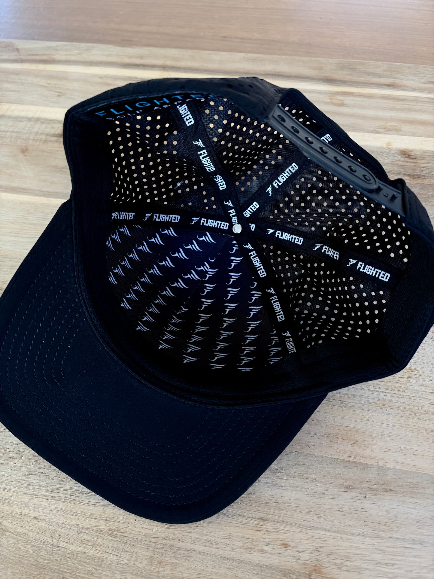 Black cap with textured back and brand logo on a wooden surface