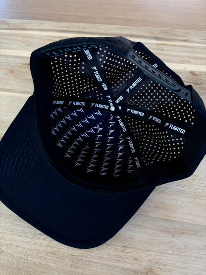 Black cap with textured back and brand logo on a wooden surface