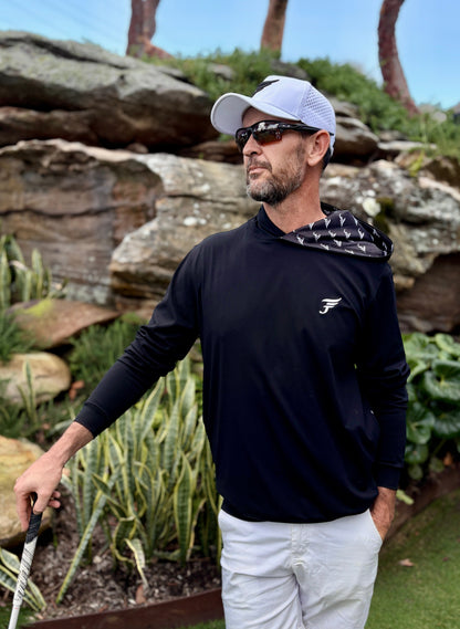 Man in golf attire standing on a golf course with rocks and plants in the background